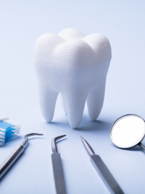 Representação do seguro odontológico. Imagem com fundo branco levemente azulado. Há um dente branco no centro e alguns matérias odontológicos no inferior da imagem.